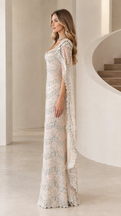 Side profile view of champagne scalloped beaded formal dress showing cape drape