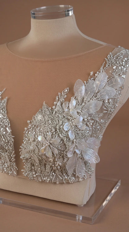 Close-up detail of sheer mesh neckline with intricate crystal beading and floral petal appliqués