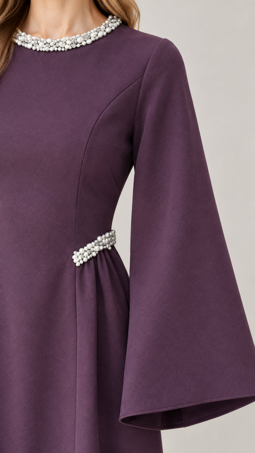 Close-up detail of pearl-embellished round neckline and waist accent on purple dress