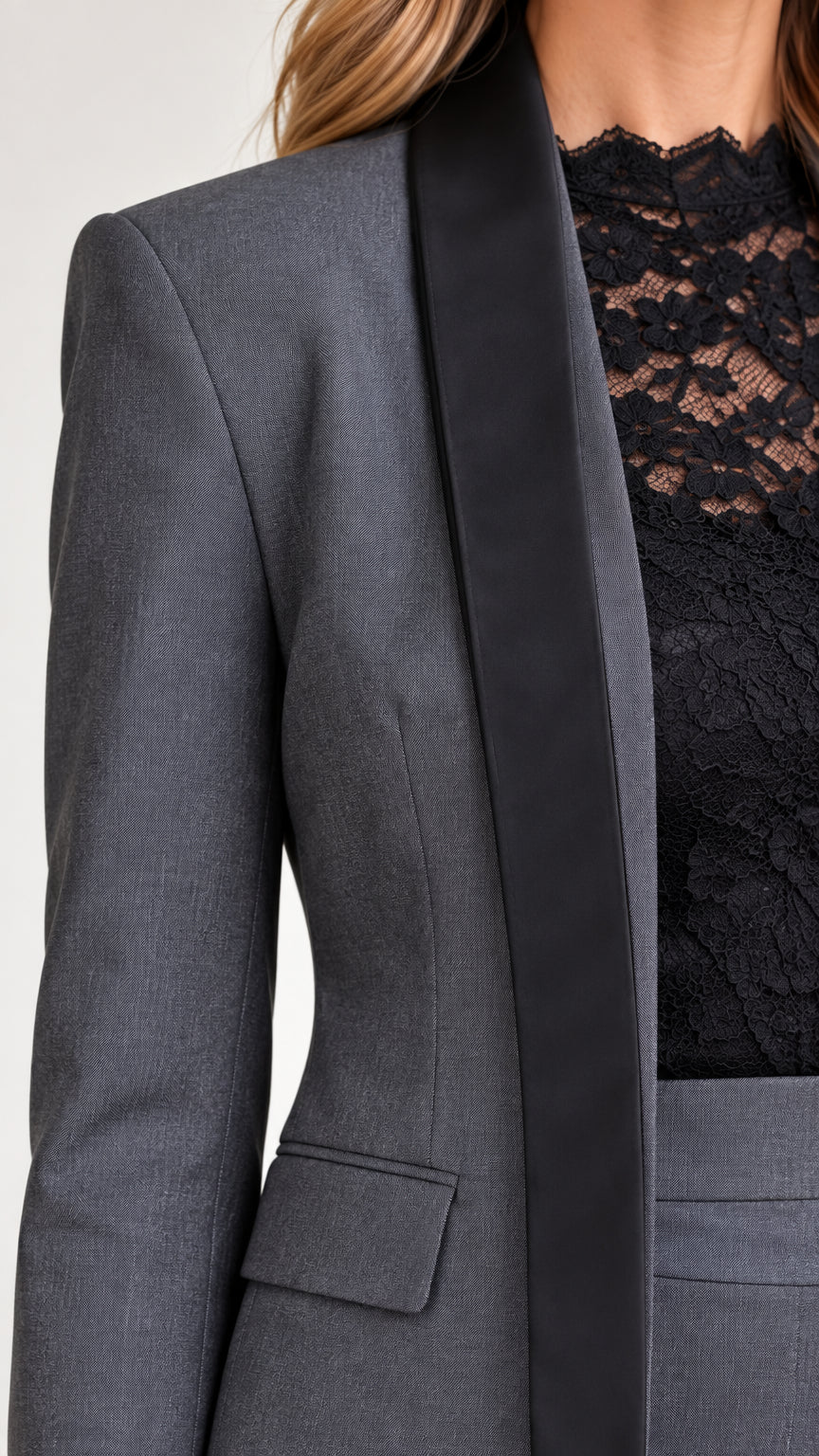Close-up detail of contrast shawl lapel, flap pocket, and floral lace neckline on charcoal grey suit