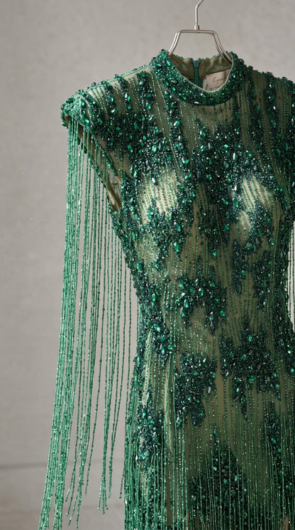Close-up detail of green beaded fringe, high neckline, and delicate sequin craftsmanship