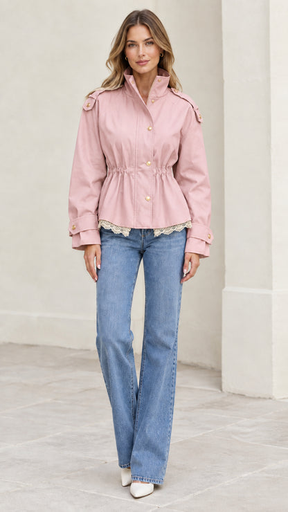Model wearing light pink cinched waist jacket with lace trim and flare jeans